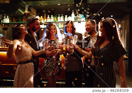 Glowing sparkles in hands. Group of happy people enjoying party with fireworks. Winter holiday. 96268309