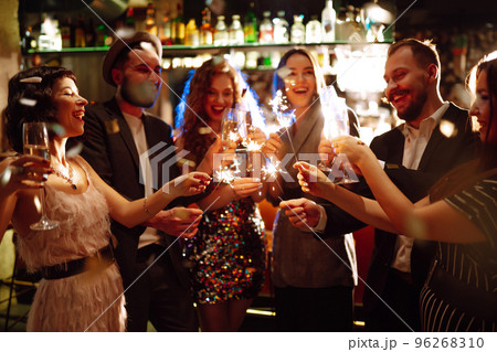 Glowing sparkles in hands. Group of happy people enjoying party with fireworks. Winter holiday. 96268310