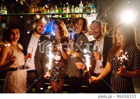 Glowing sparkles in hands. Group of happy people enjoying party with fireworks. Winter holiday. 96268315