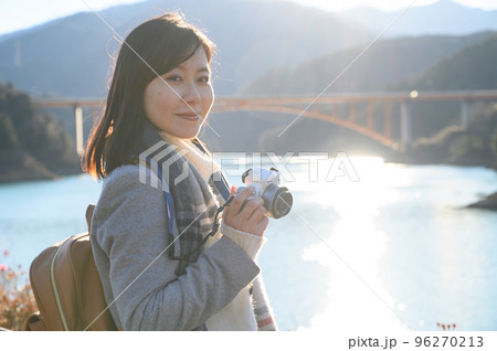 夕日の湖畔で撮影する女性 96270213