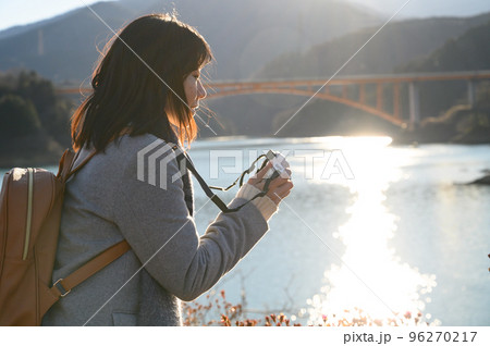 夕日の湖畔で撮影する女性 夕日の湖畔で撮影する女性 96270217