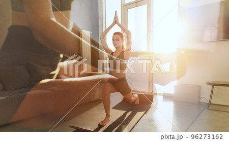 Young girl relaxing in yoga position in front of a bright window Young girl relaxing in yoga position in front of a bright window 96273162