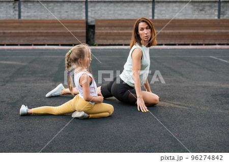 Mother and daughter go in for sports outdoors. Caucasian woman and little girl are engaged in fitness at the stadium. Mother and daughter go in for sports outdoors. Caucasian woman and little girl are engaged in fitness at the stadium. 96274842