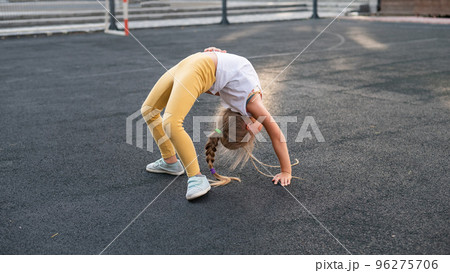 Caucasian girl doing bridge exercise on sports ground outdoors. Caucasian girl doing bridge exercise on sports ground outdoors. 96275706