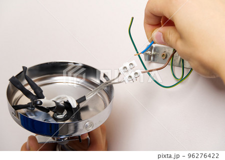 Male electrician connects the lamp on the wall. 96276422