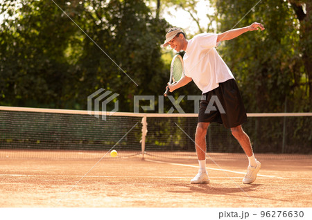 Young man in white tshirt with a tennis racket in hands Young man in white tshirt with a tennis racket in hands 96276630