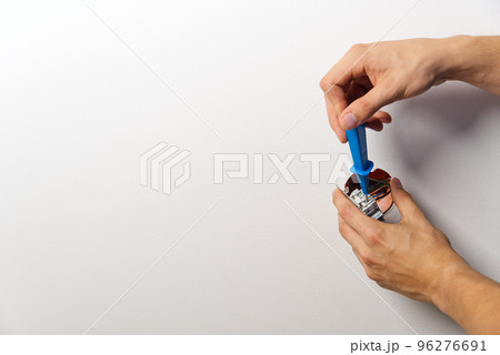 electrician installing light switch on painted wall with screwdriver. Man installing light switch after home renovation. electrician installing light switch on painted wall with screwdriver. Man installing light switch after home renovation. 96276691