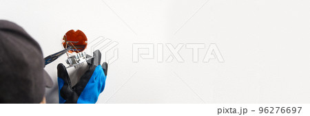 electrician installing light switch on painted wall with screwdriver. Man installing light switch after home renovation. 96276697