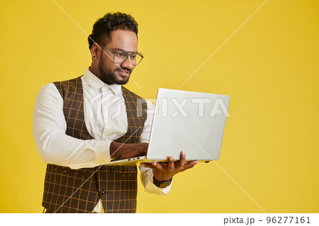 Positive project manager working on laptop, isolated on yellow 96277161