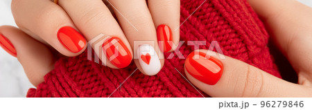 Manicured womans hands in warm wool red sweater. Fashionable valentines day nail design 96279846
