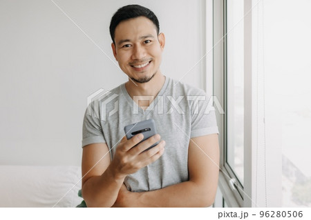 Young happy smiling asian man using smartphone feels relax and comfortable. 96280506