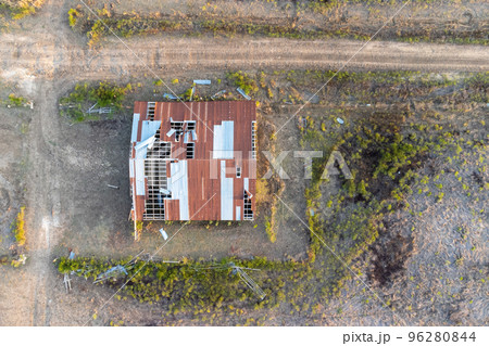 Aerial view over destroyed house with broken roof after tornado or storm. Top down, drone shot Aerial view over destroyed house with broken roof after tornado or storm. Top down, drone shot 96280844