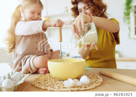 Mother and daughter prepare a cake together in the kitchen 96281925