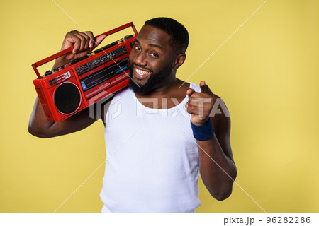 Man ears the music with an old stereo and dances. emotional and energetic expression. yellow background Man ears the music with an old stereo and dances. emotional and energetic expression. yellow background 96282286