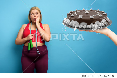 Fat girl does gym but she wants to eat a big cake. cyan background 96282510