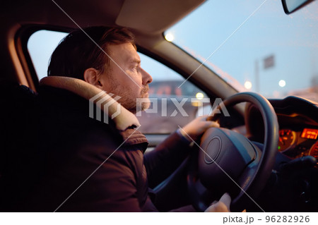 Mature man driver riding a car in city on cold winter evening. Taxi driver waiting client passanger. Inside view. 96282926
