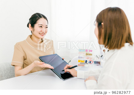 ネイルサロンでタブレットの契約書に電子サインするカウンセラースタッフと相談する日本人女性 ネイルサロンでタブレットの契約書に電子サインするカウンセラースタッフと相談する日本人女性 96282977
