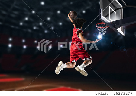Basketball player in red uniform jumping high to make a slam dunk to the basket 96283277
