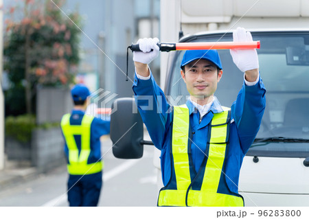 路上で交通誘導する警備員 96283800