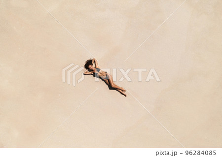 Top Aerial Drone View of Woman in Swimsuit Bikini Relaxing and Sunbathing on Beach White Sand Top Aerial Drone View of Woman in Swimsuit Bikini Relaxing and Sunbathing on Beach White Sand 96284085
