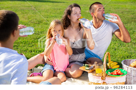 Parents with two teenagers enjoying delicious meal on the picnic Parents with two teenagers enjoying delicious meal on the picnic 96284113