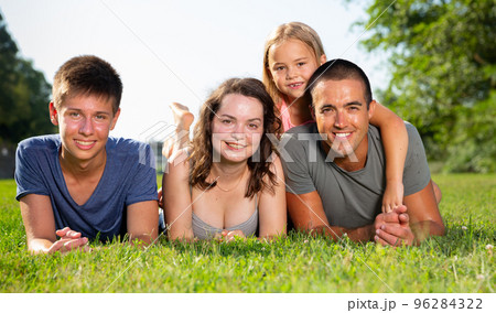 Portrait of positive family on green lawn in summer park 96284322