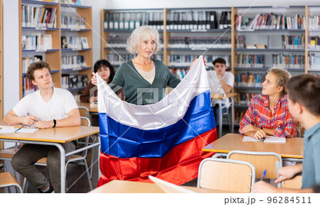 Interesting story about Russia while teaching high school students in school library. Teacher holds flag of Russia in her hands Interesting story about Russia while teaching high school students in school library. Teacher holds flag of Russia in her hands 96284511