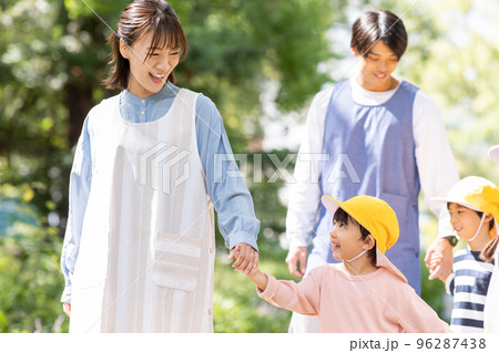 公園を散歩する保育士と園児 96287438
