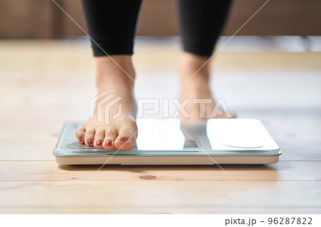 体重計に乗るアジア人女性の足元 96287822
