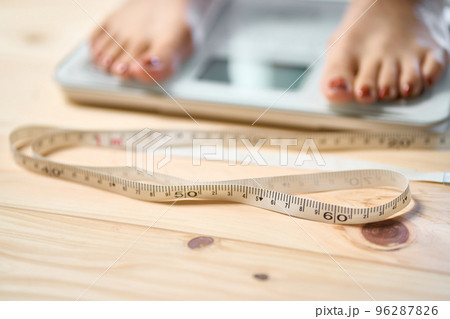 メジャーと体重計に乗る女性の足元 メジャーと体重計に乗る女性の足元 96287826