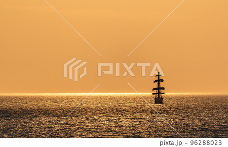 A red burning sunset with the silhouette of sailing ship. Sailors set sails on masts of ship. White sailing vessel floating in the sea. Copy space. A red burning sunset with the silhouette of sailing ship. Sailors set sails on masts of ship. White sailing vessel floating in the sea. Copy space. 96288023