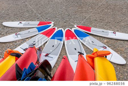 Sup board and kayaks rental place on the beach. Surfboards, many different surf boards on the beach, water sport, happy active summer vacation. Row of stand up paddle boards ready to rent. 96288036