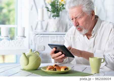 senior man using tablet while drinking tea 96288604