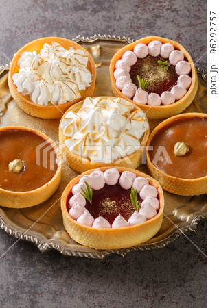 set of sweet tartlets for the holiday with lemon curd, raspberry curd, nuts and chocolate close-up on a plate. Vertical set of sweet tartlets for the holiday with lemon curd, raspberry curd, nuts and chocolate close-up on a plate. Vertical 96292757