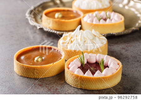 Delicious gourmet sweets tartlets for the holiday with meringue and lemon curd, raspberry curd, nuts and chocolate close-up. Horizontal Delicious gourmet sweets tartlets for the holiday with meringue and lemon curd, raspberry curd, nuts and chocolate close-up. Horizontal 96292758