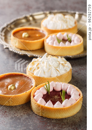 Festive mix tartlets with lemon curd, raspberry curd, nuts and chocolate close-up. Vertical Festive mix tartlets with lemon curd, raspberry curd, nuts and chocolate close-up. Vertical 96292759