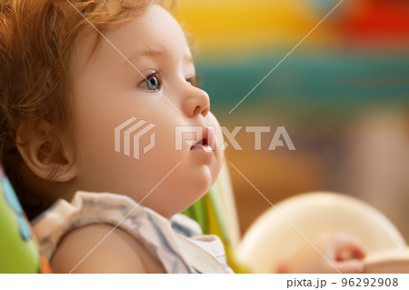 The baby sits on a highchair and waits for the 96292908