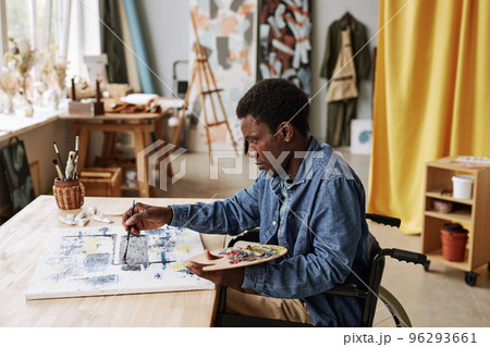 Portrait of young diligent art school student in wheelchair painting on canvas Portrait of young diligent art school student in wheelchair painting on canvas 96293661