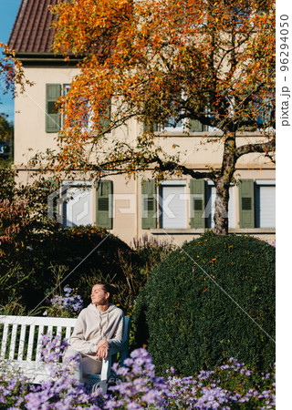 A Girl Sits On A Bench In The Park And Enjoys The Sun. Portrait Young Adult Attractive Woman Enjoy Sitting On Bench And Relaxing Calm Carefree Rest In City Park Against Green Grass And Trees On Sunny 96294050