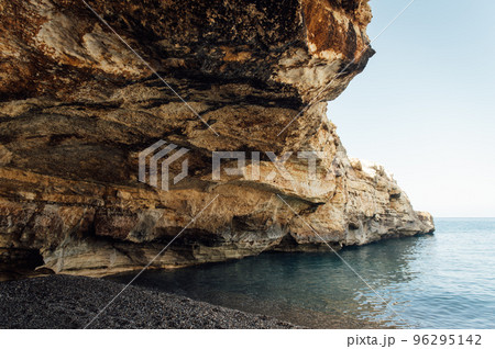 Massive rocks sink into the water on a pebble beach Massive rocks sink into the water on a pebble beach 96295142