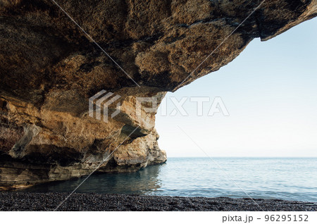 Massive rocks sink into the water on a pebble beach 96295152