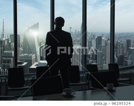 Side view of a businessman looking at skyscrapers through window 96295524