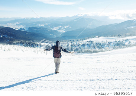Man with backpack trekking in mountains. Cold weather, snow on hills. Winter hiking. 96295617