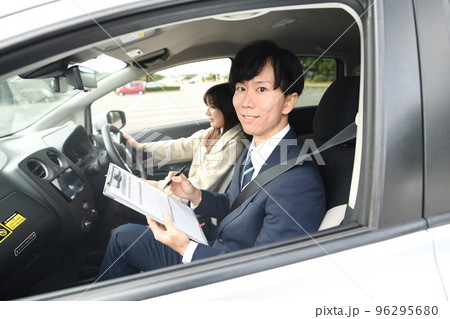 車の運転教習をする男性教官と女性生徒 車の運転教習をする男性教官と女性生徒 96295680