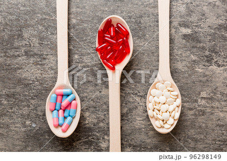 Vitamin capsules in a spoon on a colored background. Pills served as a healthy meal. Red soft gel vitamin supplement capsules on spoon Vitamin capsules in a spoon on a colored background. Pills served as a healthy meal. Red soft gel vitamin supplement capsules on spoon 96298149