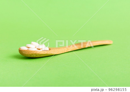 Heap of white pills on colored background. Tablets scattered on a table. Pile of red soft gelatin capsule. Vitamins and dietary supplements concept Heap of white pills on colored background. Tablets scattered on a table. Pile of red soft gelatin capsule. Vitamins and dietary supplements concept 96298155