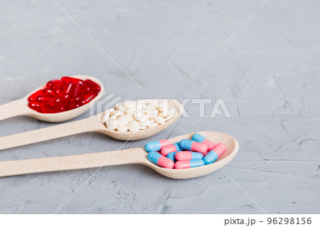 Vitamin capsules in a spoon on a colored background. Pills served as a healthy meal. Red soft gel vitamin supplement capsules on spoon Vitamin capsules in a spoon on a colored background. Pills served as a healthy meal. Red soft gel vitamin supplement capsules on spoon 96298156