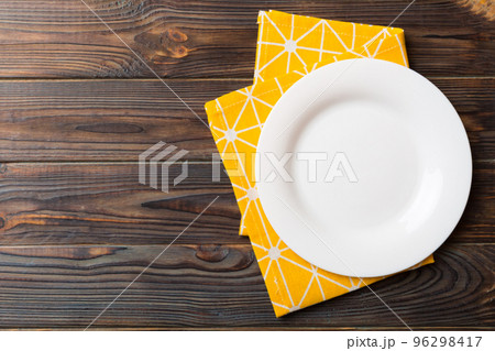 Top view on colored background empty round white plate on tablecloth for food. Empty dish on napkin with space for your design Top view on colored background empty round white plate on tablecloth for food. Empty dish on napkin with space for your design 96298417