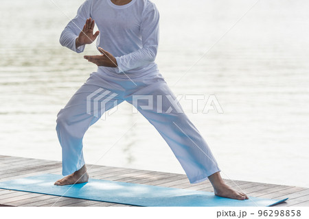 Young man practicing traditional Tai Chi Chuan, Tai Ji and Qi gong in the park for healthy, traditional chinese martial arts concept on natural background . Young man practicing traditional Tai Chi Chuan, Tai Ji and Qi gong in the park for healthy, traditional chinese martial arts concept on natural background . 96298858