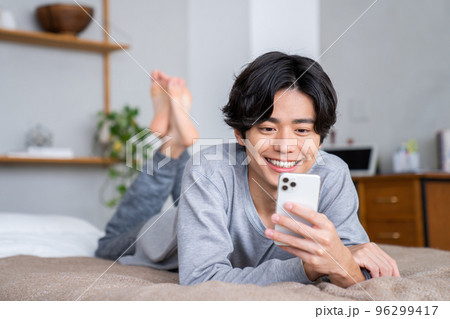 スマホを見る若い男性　 96299417